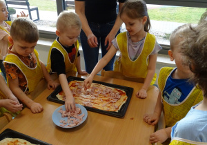 Dzieci kładą szynkę na pizzę