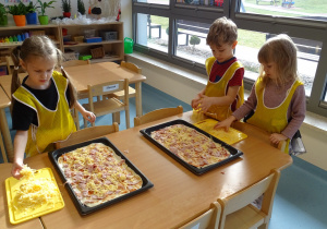 Dzieci kładą ser na pizzę