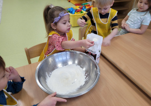 Dziewczynka sypie mąkę do miski