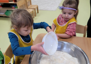 Dziewczynka dodaje wyrośnięte drożdże do miski z mąką