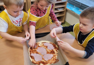 Dzieci układają dodatki na pizzę