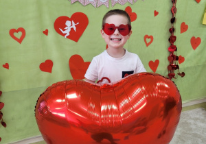 Antoś w okularach w kształcie serca trzyma duży balon serce