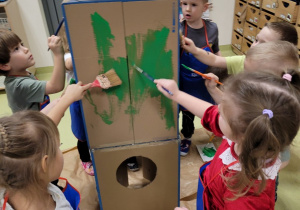 Dzieci malują rakietę zrobioną z kartonów
