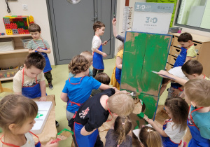 Dzieci malują rakietę zrobioną z kartonów