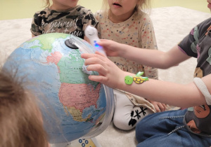 Dzieci oglądają model Ziemi z albikiem