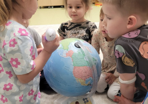Dzieci oglądają model Ziemi z albikiem
