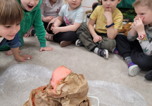 Dzieci siedzą wokół wulkanu z papieru