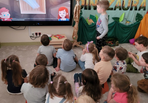 Dzieci oglądają filmik o dinozaurach