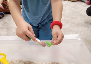 Dzieci poszukują w piasku kinetycznym figurek dinozaura