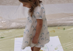 Dziewczynka maluje stopami dinozaura