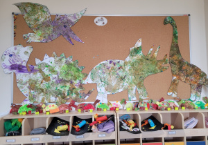 Pomalowane dinozaury wiszą w galerii prac dzieci