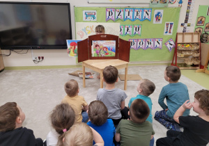 Pani Ilonka czyta dzieciom bajkę używając teatrzyku kamishibai