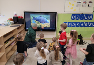 Dzieci oglądają wyświetlane zdjęcia ryb