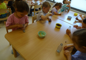 01 Dzieci wsypują różnorodny materiał do butelek plastikowych i jajeczek