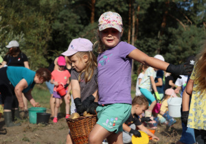 dziewczynki niosą pełen kosz ziemniaków