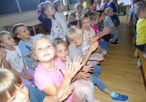 Dzieci siedzą na ławeczkach, oglądają przedstawienie