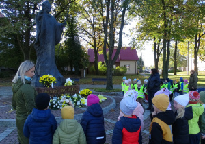 dzieci stoją pod pomnikiem Jana Pawła II