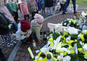 Dzieci stawiają znicz pod pomnikiem Jana PawłaII