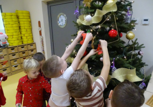 Dzieci wieszają ozdoby na choinkę