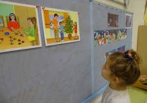01 Dziewczynka patrzy na obrazki z tradycjami Świąt Bożego Narodzenia