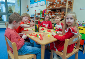 Dzieci wyklejają serduszka za pomocą bibuły