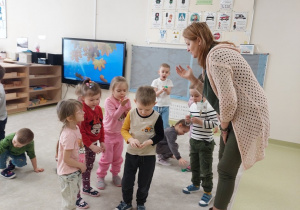 Logopeda prezentuje dzieciom ćwiczenie z piórkiem