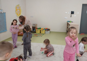 Dzieci wykonują ćwiczenia oddechowe z piórkiem