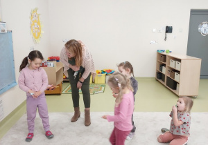 Dziewczynka z dziećmi wykonuje ćwiczenie z piórkiem