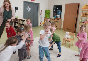 Dzieci wykonują ćwiczenie z piórkiem