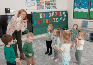 Logopeda prezentuje dzieciom ćwiczenie oddechowe z piórkiem
