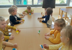 Dzieci siedzą przy stoliku i mają przed sobą żaglówki