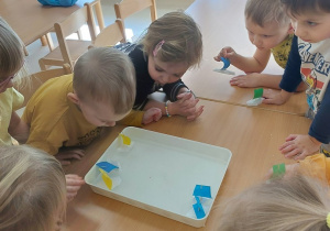 Dzieci wykonują ćwiczenia oddechowe z żaglówkami na wodzie