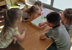 Dzieci wykonują ćwiczenia oddechowe z pływającymi żaglówkami