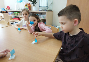 Dzieci przy stoliku pokazują wykonane żaglówki