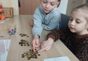 Dziewczynka i chłopiec wskazują, gdzie jest większa góra grosza