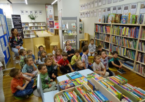 Dzieci siedzą na dywanikach w bibliotece
