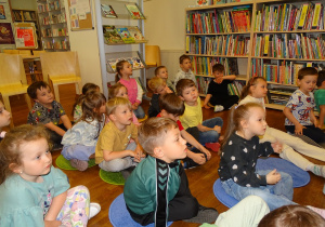 Dzieci z zainteresowaniem słuchają bibliotekarki