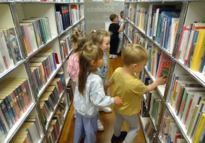Dzieci olądądają książki na półkach