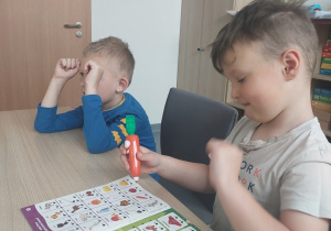 Chłopcy rozwiązują zadnia w książce z Magiczną Marchewką