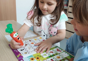 Dziewczynka zaznacza odpowiedź w kolorowych zagadkach