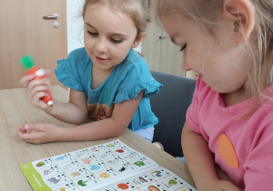 Dziewczynki rozwiązują zadnia w książce z Magiczną Marchewką