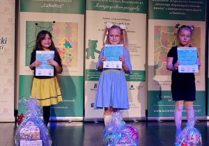 Julka z dziewczynkami pokazują dyplomy i nagrody