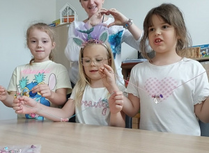 Trzy dziewczynki z logopedą prezentują wykonane naszyjniki i bransoletki