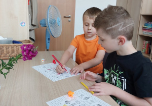 Chłopcy przy stole wyliczają pola i kolorują je