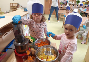 Dzieci wkładają warzywa do wyciskarki.