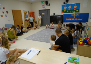 dzieci siedzą na dywanie z rodzicami