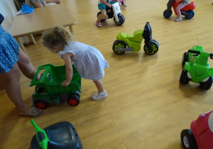 dzieci jeżdżą na jeździkach na sali gimnastycznej