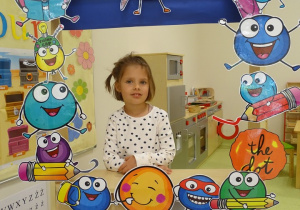 Dziewczynka pozuje do zdjęcia w kropkowej ramce.