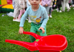 Dziecko prowadzi taczkę z piłeczką.