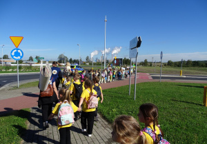 Korowód dzieci z transparentami idzie chodnikiem